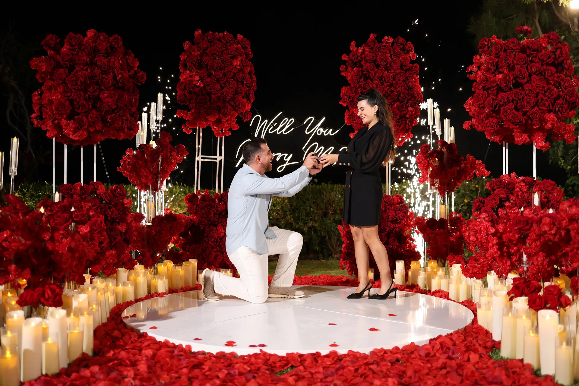 Camp Pink proposal scene with a dramatic rose installation, candlelight, and nighttime sparkle effects.